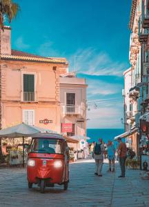 a small red car parked on a street with people at Pieno Centro Apartment in Tropea