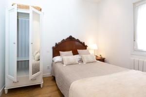 Habitación blanca con cama y espejo en Old Town by Bilbao Living, en Bilbao