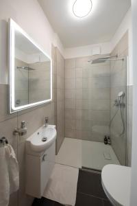 ein Badezimmer mit Waschbecken und Dusche mit Spiegel in der Unterkunft JayBnB - Apartment direkt am Hafen mit Terrasse und UHD TV in Dortmund