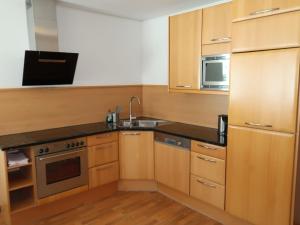 a kitchen with wooden cabinets and a sink and a microwave at Apartment Altes Zollhaus-4 by Interhome in Nauders