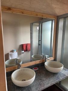 La salle de bains est pourvue de 3 lavabos et d'un miroir. dans l'établissement The Coffee Lodge at Clarke Farm, à Fort Portal