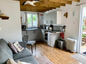a living room with a couch and a kitchen at 'The Wheelhouse' Nautically themed with large sleeping deck in Southwold