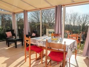 a dining table and chairs on a patio with windows at Holiday Home Kerguntuil - PBU311 by Interhome in Pleumeur-Bodou