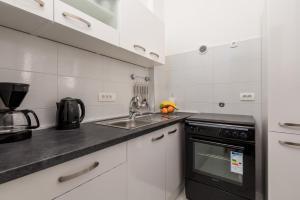 a white kitchen with a sink and a stove at Apartman Jasmina 2 in Rijeka