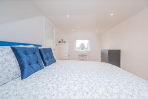 une chambre blanche avec un grand lit avec des oreillers bleus dans l'établissement 4 Bed cottage with Hot tub, à Bannockburn 13 autres photos