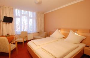 a hotel room with a bed and a table and a window at Hotel Münchner Löwenbräu in Cuxhaven