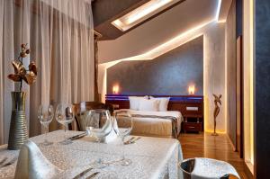 um quarto de hotel com duas camas e duas mesas com copos de vinho em National Palace Spa & Wellness Hotel em Sliven