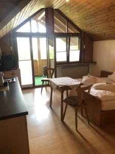 ein Wohnzimmer mit einem Tisch, einem Bett und einem Fenster in der Unterkunft Landhaus Monika in Meckenbeuren