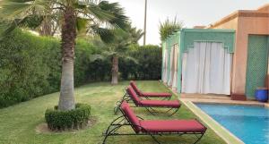 a group of red chairs sitting next to a pool at Villa Gardens in Douar Soukkane