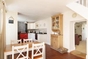 a kitchen with a table and a kitchen with red cabinets at Windy Ridge Cottage - 5 Bedroom Holiday Home - Oxwich in Oystermouth