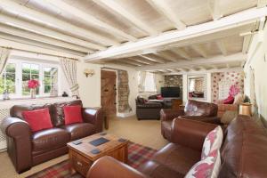 a living room with leather couches and a tv at Windy Ridge Cottage - 5 Bedroom Holiday Home - Oxwich in Oystermouth