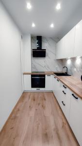 a kitchen with white cabinets and a wooden counter top at Złote Apartamenty 36 in Legnica