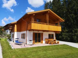 a large wooden house with a patio and a deck at Feriendorf Via Claudia Haus 78 Platzhirsch in Lechbruck