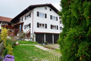 a white house with black windows and a yard at "Beim Brugger" in Lechbruck