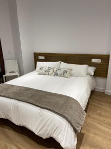 a bedroom with a large bed with white sheets and pillows at Estrada Suites in Ávila