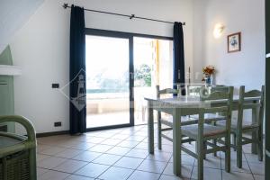 a dining room with a table and chairs and a window at 18 BAIA FARO - Grazioso bilocale mansardato a Baia del Faro in Palau +3 photos