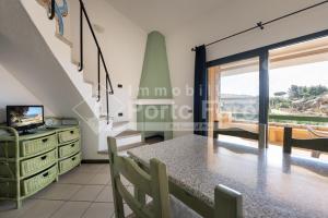 a living room with a dining room table and a television at 18 BAIA FARO - Grazioso bilocale mansardato a Baia del Faro in Palau