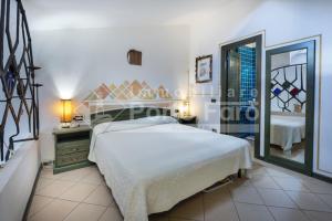 1 dormitorio con 1 cama grande y espejo en 23 BAIA FARO - Trilocale mansardato con ampia terrazza vista mare en Palau