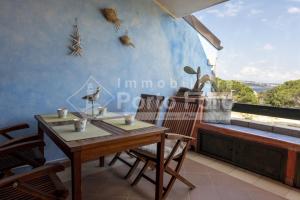 23 BAIA FARO - Trilocale mansardato con ampia terrazza vista mare في بالاو: غرفة طعام مع طاولة وكراسي ونافذة