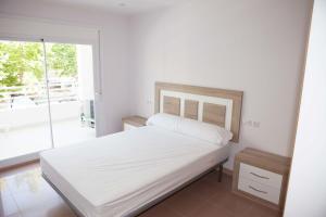 ein weißes Schlafzimmer mit einem Bett und einem Balkon in der Unterkunft COSTA DAURADA APARTAMENTS - Royal 106 Luxe in Salou