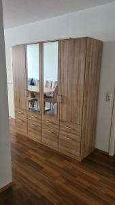 a large wooden cabinet in a living room with a table at Familien-Ferienwohnung Fiwa FeWo-4 in Pirmasens +8 photos
