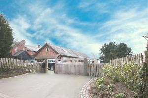 a house with a wooden fence and a driveway at The Hayloft in Crewe