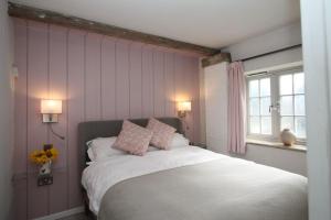 a bedroom with a bed with pink walls and a window at The Hayloft in Crewe