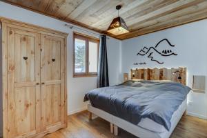 sypialnia z łóżkiem i drewnianym sufitem w obiekcie Les Nards w mieście Praz-sur-Arly