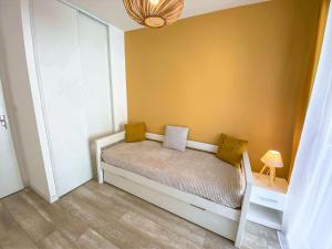 um pequeno quarto com uma cama com paredes amarelas em Apartment Confidence 2 by Interhome em Dinard