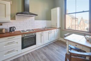 a kitchen with white cabinets and a table and a window at Host & Stay - Milton Street Apartments in Saltburn-by-the-Sea