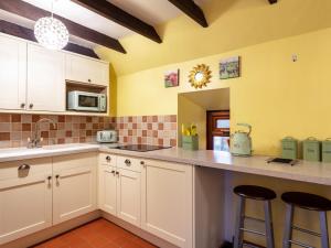 a kitchen with white cabinets and a counter with stools at Holiday Home Deveron Valley Cottages by Interhome in Marnoch