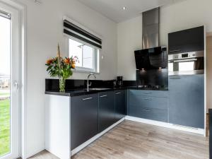 una cocina con armarios negros y fregadero en Holiday Home Green Resort Mooi Bemelen by Interhome, en Bemelen