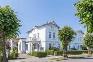 een groot wit huis met bomen ervoor bij Strandstraße 16 Wohnung 09 in Kühlungsborn