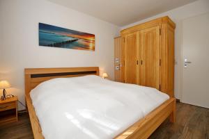 um quarto com uma cama branca e um armário de madeira em Strandstraße 16 Wohnung 14 em Kühlungsborn