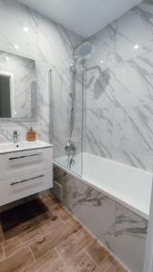 baño blanco con ducha y lavamanos en Złote Apartamenty 58, en Legnica