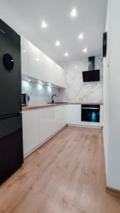a large kitchen with white cabinets and a wooden floor at Złote Apartamenty 58 in Legnica