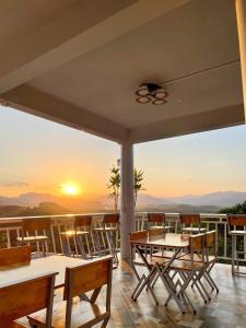 a patio with tables and chairs with a sunset in the background at 99 Camp and Cafe in Khao Sok