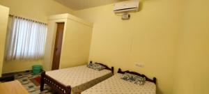 1 dormitorio con 2 camas, ventana y calentador en Peniel Residency, en Kochi