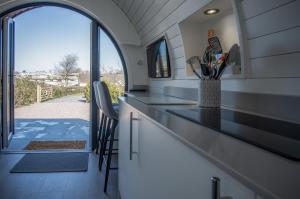 a kitchen with a counter with chairs and an open door at Bracken Burrows - 1 Bedroom Pod - New Hedges in New Hedges
