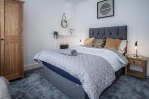 a bedroom with a large bed with a blue comforter at Hawtree Cottage - 2 Bedroom Cottage - Tenby in Tenby