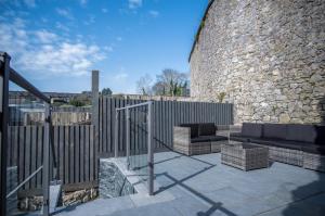 a patio with a couch and chairs next to a stone wall at Hawtree Cottage - 2 Bedroom Cottage - Tenby in Tenby