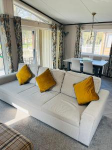 a living room with a white couch with yellow pillows at Brackencroft Lodge with Hot Tub in York +12 photos