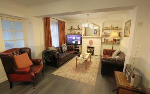 a living room with leather furniture and a tv at The Corner House - Historic Character Cottage in the Forest in Coleford