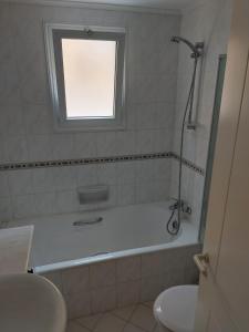 a bathroom with a tub and a sink and a window at Aphrodite Springs in Paphos City
