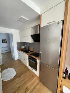 a kitchen with a stainless steel refrigerator and wooden floors at Sea Gem Apartment in Dhërmi