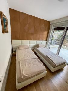 two beds in a room with a window at Sea Gem Apartment in Dhërmi