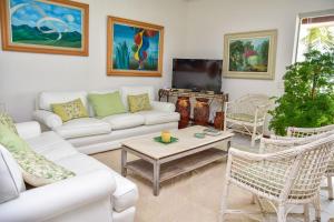 ein Wohnzimmer mit weißen Möbeln und einem Flachbild-TV in der Unterkunft Casa beira mar na Praia da Enseada no Guaruja SP in Guarujá