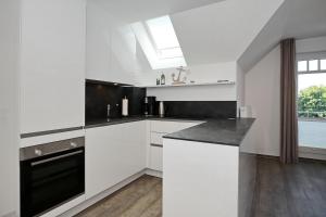 a kitchen with white cabinets and a black counter top at Villa Hanse Wohnung 319 in Kühlungsborn