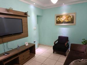 ein Wohnzimmer mit einem Flachbild-TV und einem Stuhl in der Unterkunft 10 MIN AEROPORTO GUARULHOS in Guarulhos