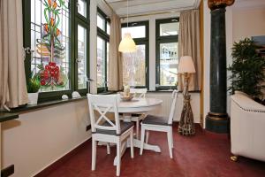 ein Esszimmer mit einem Tisch, Stühlen und Fenstern in der Unterkunft Villa Laura Wohnung 01 in Kühlungsborn